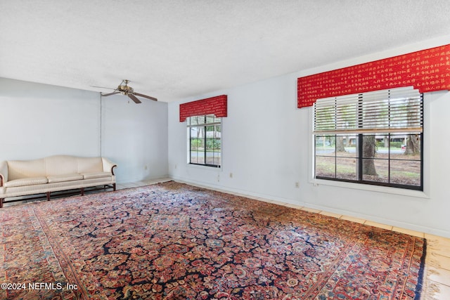 unfurnished living room with ceiling fan and a textured ceiling