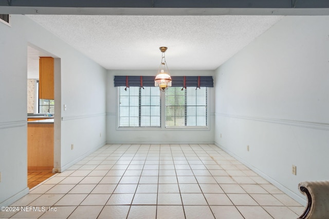 unfurnished dining area featuring a textured ceiling and light tile patterned floors