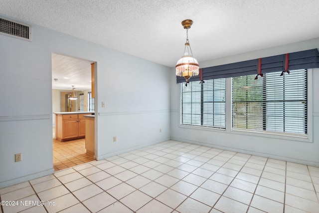 unfurnished dining area with light tile patterned floors, a chandelier, and a textured ceiling