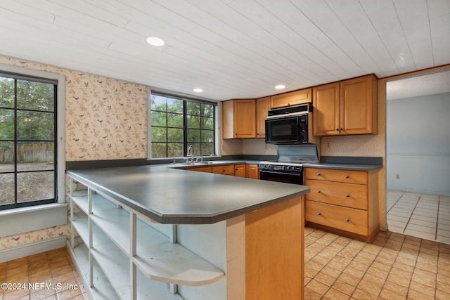 kitchen featuring a kitchen breakfast bar, black appliances, light tile patterned flooring, sink, and kitchen peninsula