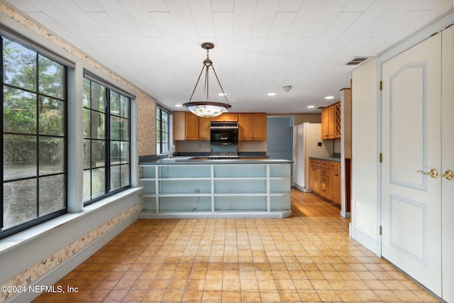 kitchen featuring decorative light fixtures, white fridge, sink, oven, and kitchen peninsula