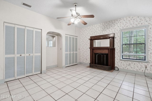 unfurnished living room with lofted ceiling, light tile patterned flooring, and ceiling fan