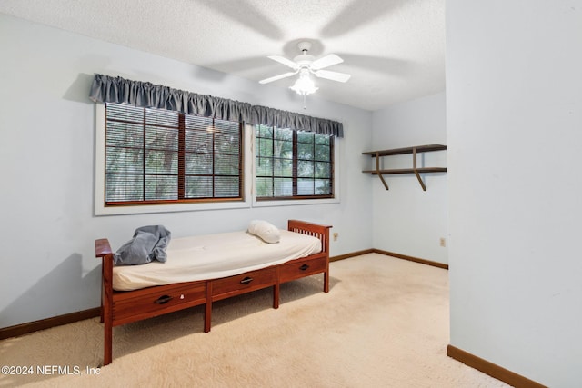 bedroom featuring light carpet, ceiling fan, and a textured ceiling