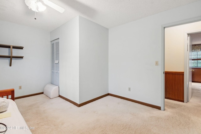 unfurnished bedroom featuring ceiling fan, a closet, a textured ceiling, and light colored carpet