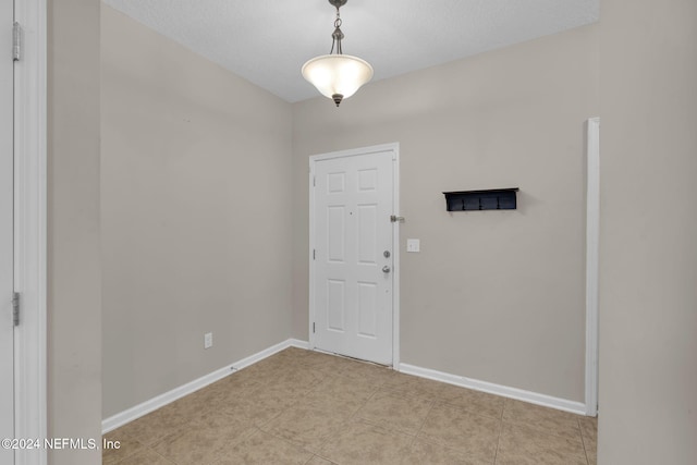 foyer with a textured ceiling, baseboards, and light tile patterned floors