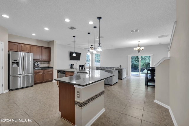 kitchen with appliances with stainless steel finishes, dark countertops, a sink, and visible vents