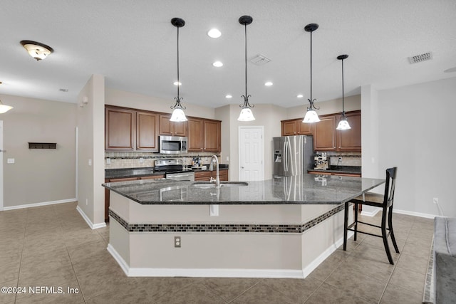 kitchen with a large island, stainless steel appliances, visible vents, decorative backsplash, and a sink