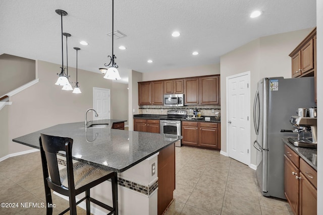 kitchen featuring a breakfast bar, stainless steel appliances, tasteful backsplash, a sink, and a large island with sink