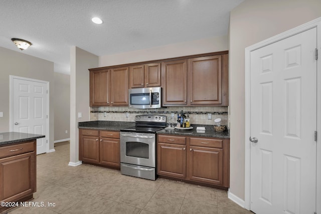 kitchen with light tile patterned floors, appliances with stainless steel finishes, brown cabinetry, and decorative backsplash