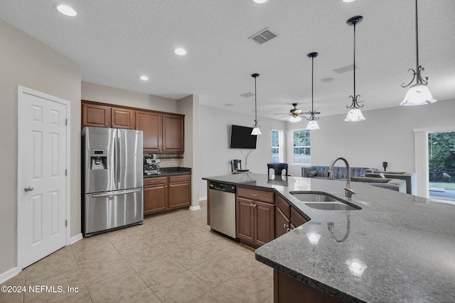 kitchen featuring a sink, visible vents, appliances with stainless steel finishes, dark stone countertops, and pendant lighting