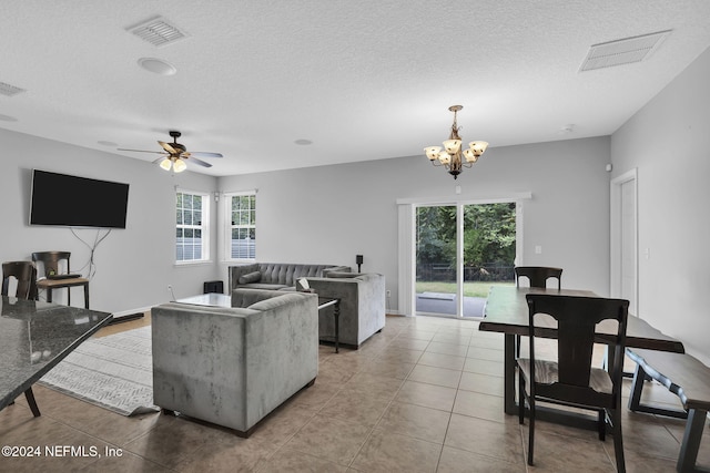 tiled living room featuring visible vents, a textured ceiling, and ceiling fan with notable chandelier