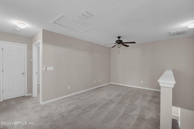 spare room featuring attic access, a textured ceiling, visible vents, and carpet flooring