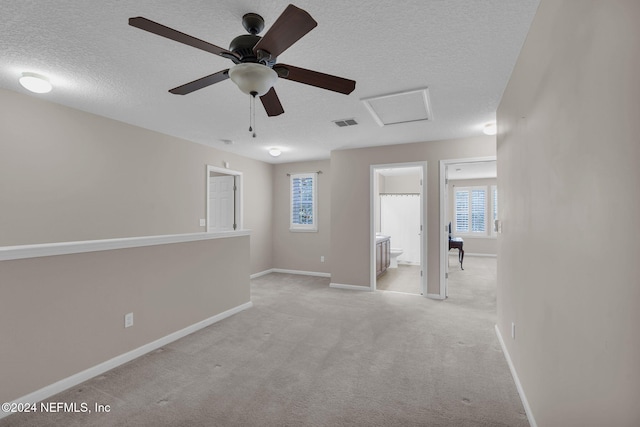 unfurnished room featuring attic access, visible vents, a textured ceiling, and baseboards