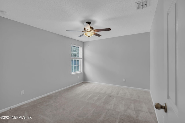 carpeted empty room featuring a textured ceiling, ceiling fan, visible vents, and baseboards