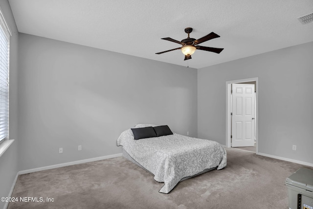 carpeted bedroom featuring a textured ceiling, a ceiling fan, visible vents, and baseboards