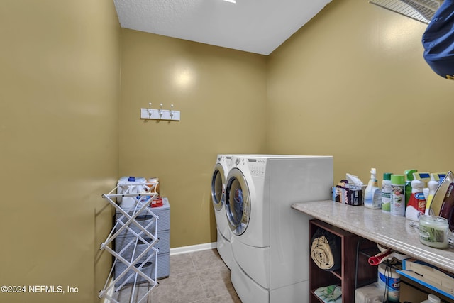 laundry area with laundry area, washing machine and dryer, baseboards, and tile patterned flooring