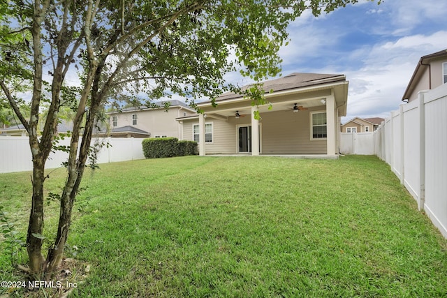 rear view of property featuring a ceiling fan, a fenced backyard, and a yard