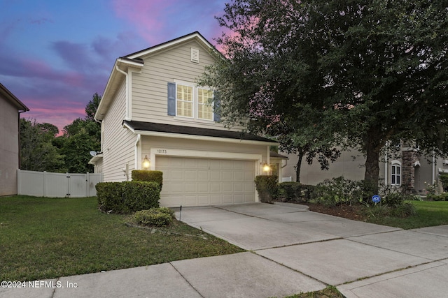 traditional-style home with concrete driveway, a front lawn, an attached garage, and fence