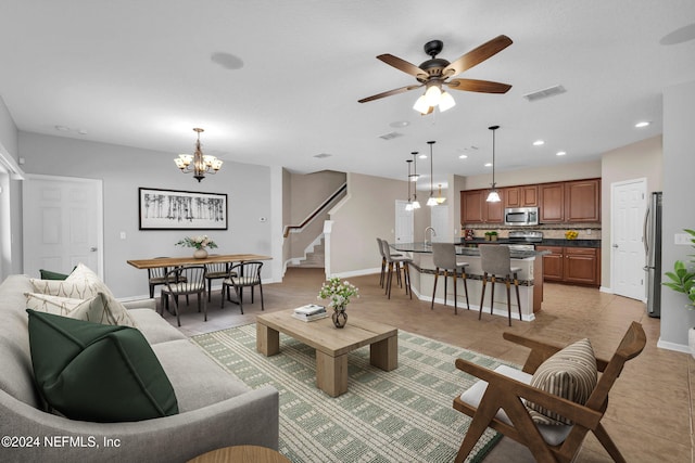 living room featuring stairs, light tile patterned floors, visible vents, and baseboards