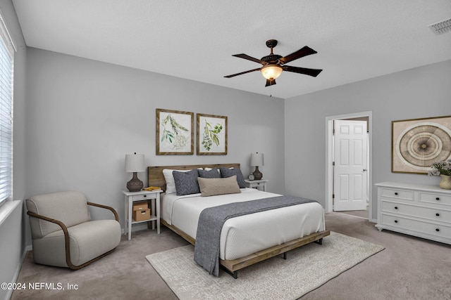 bedroom featuring a textured ceiling, carpet, visible vents, and a ceiling fan