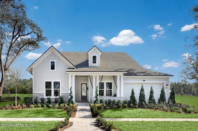 view of front of property featuring a front yard, a porch, and a garage