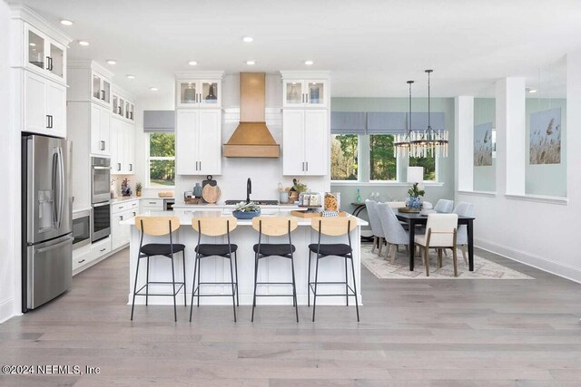 55 Sparrow Crk Dr, Saint Augustine, FL 32092 - kitchen with stainless steel appliances, wall chimney exhaust hood, light wood-style flooring, a kitchen island with sink, and recessed lighting