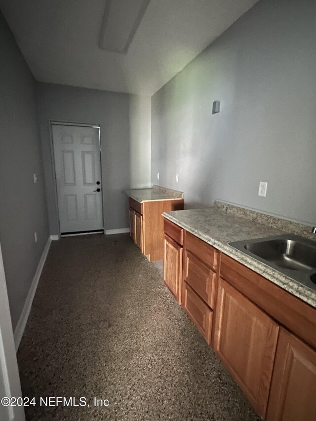 2122 Ashland St, Jacksonville, FL 32207 - kitchen featuring a sink, brown cabinetry, and baseboards