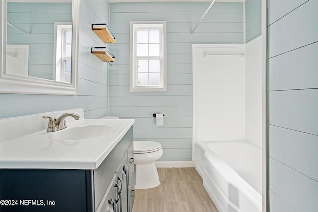 full bathroom featuring washtub / shower combination, wood-type flooring, vanity, wooden walls, and toilet