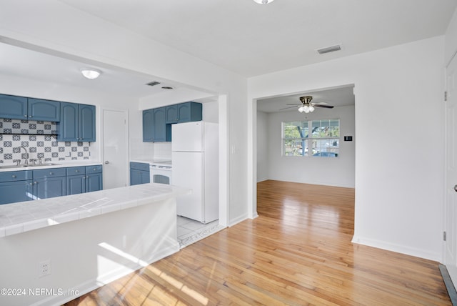 kitchen featuring light hardwood / wood-style floors, tile countertops, decorative backsplash, ceiling fan, and white appliances