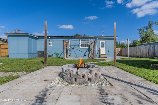 back of property with central air condition unit, an outdoor fire pit, a lawn, and a patio area