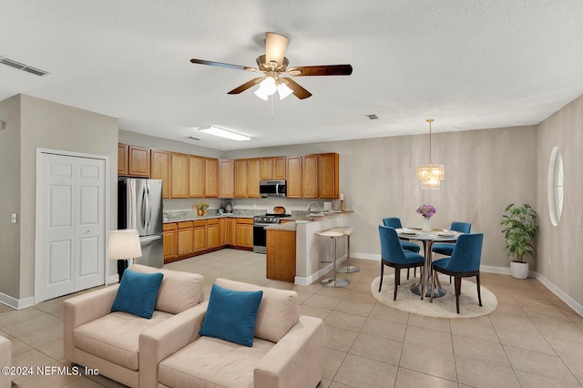 kitchen with kitchen peninsula, sink, light tile patterned floors, pendant lighting, and appliances with stainless steel finishes