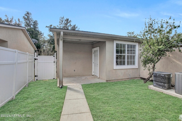 doorway to property featuring central AC unit and a lawn