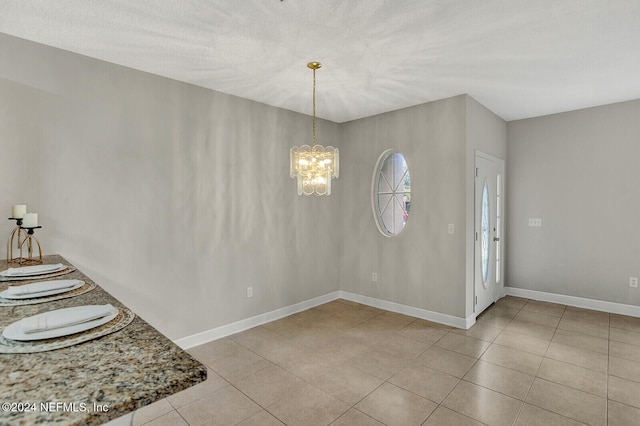 tiled entryway featuring an inviting chandelier