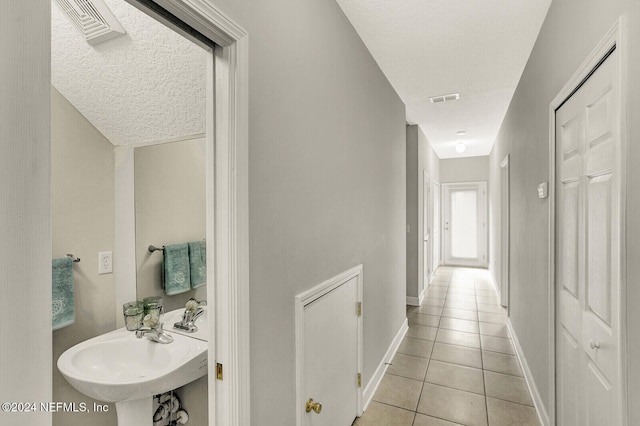 interior space with a textured ceiling, tile patterned floors, and sink