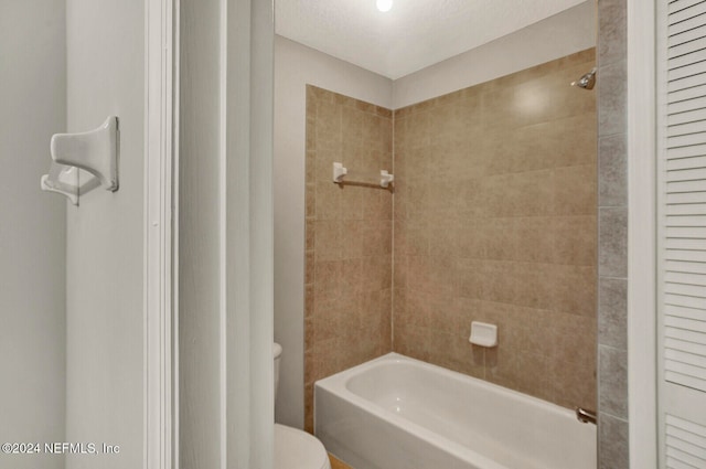 bathroom featuring toilet and tiled shower / bath