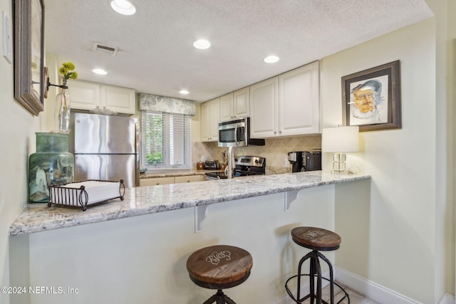 kitchen with a kitchen bar, appliances with stainless steel finishes, and light stone counters