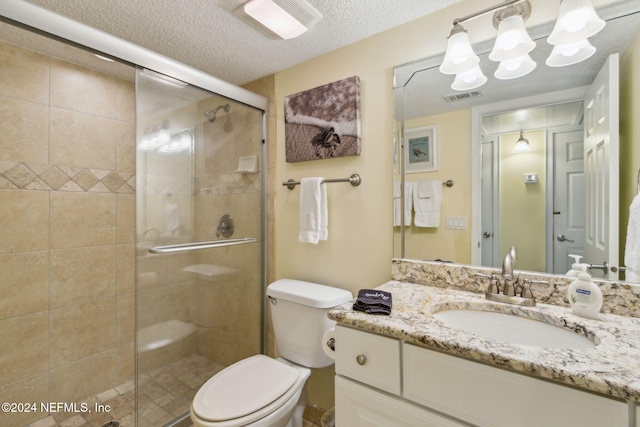 bathroom featuring toilet, vanity, a textured ceiling, and a shower with shower door