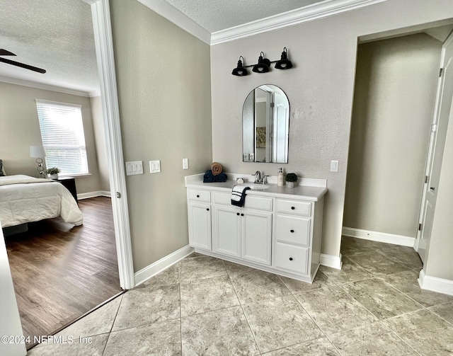 bathroom featuring vanity, hardwood / wood-style flooring, ceiling fan, ornamental molding, and a textured ceiling