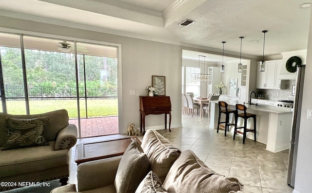 tiled living room with ceiling fan, crown molding, a textured ceiling, and sink