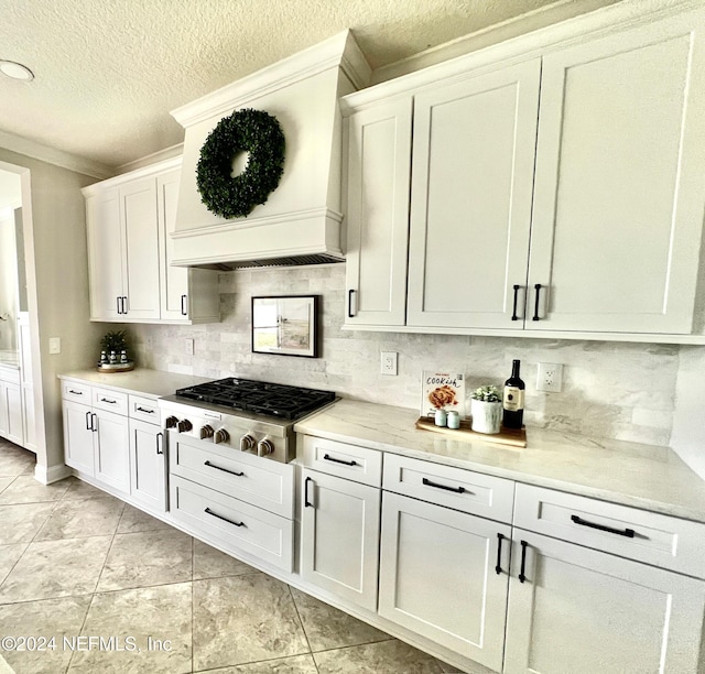 kitchen featuring tasteful backsplash, white cabinetry, stainless steel gas cooktop, and light tile patterned flooring