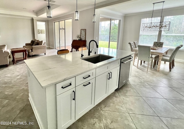 kitchen with pendant lighting, white cabinets, sink, an island with sink, and light stone counters