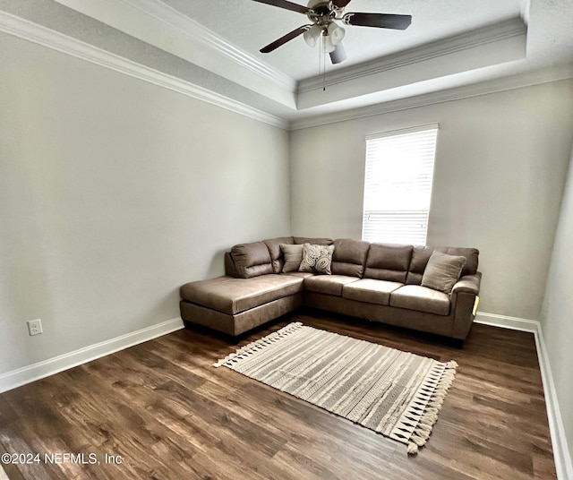 living room with a raised ceiling, ceiling fan, dark hardwood / wood-style flooring, and crown molding