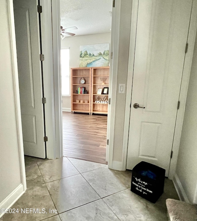 hallway with light hardwood / wood-style floors and a textured ceiling