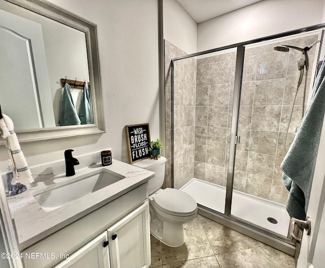 bathroom with tile patterned floors, vanity, toilet, and a shower with door