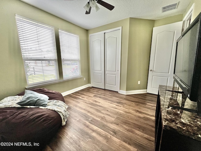 bedroom featuring hardwood / wood-style flooring, ceiling fan, a closet, and multiple windows