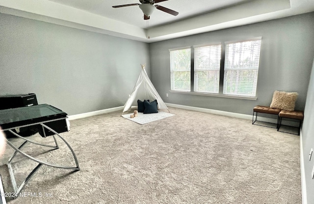 rec room featuring a raised ceiling, ceiling fan, and carpet floors