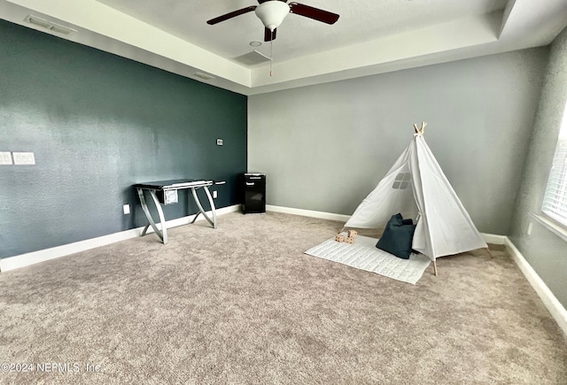 playroom featuring a raised ceiling, ceiling fan, and light colored carpet