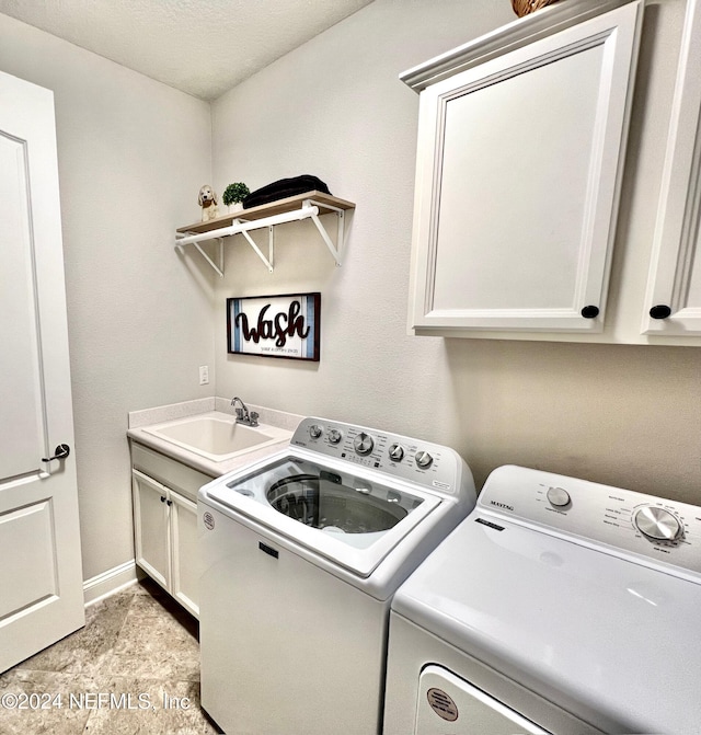 laundry room featuring cabinets, a textured ceiling, separate washer and dryer, and sink