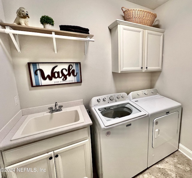 laundry area featuring washer and clothes dryer, sink, and cabinets