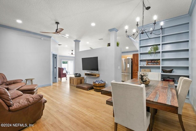 dining space featuring ceiling fan with notable chandelier, a textured ceiling, decorative columns, and light hardwood / wood-style flooring